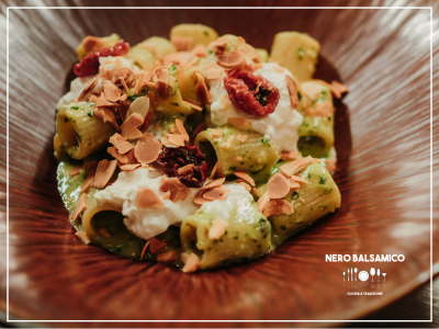 Mezze maniche pasta from "Mancini" with arugula and pine nut pesto, stracciatella, confit cherry tomatoes, and toasted almonds